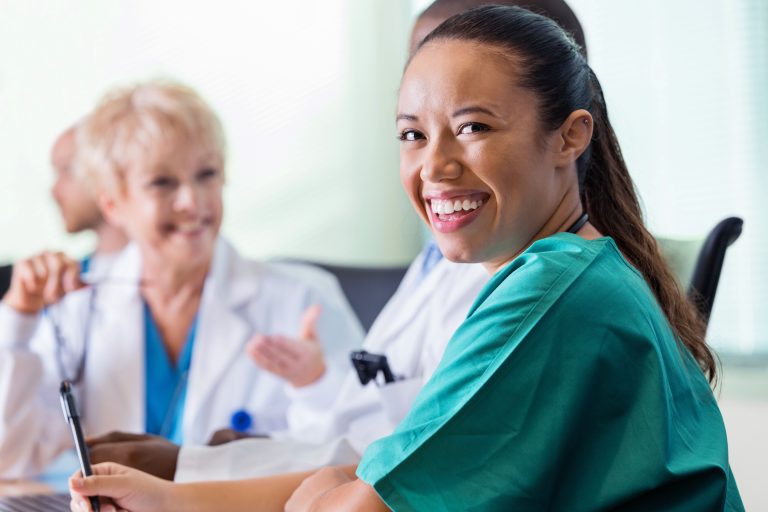 Happy doctor or nurse looking back during hospital meeting