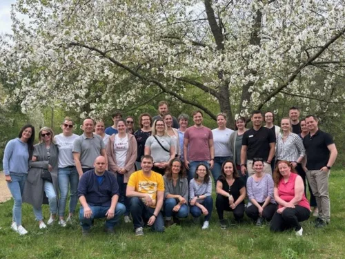 a group of masters students standing outside, in front of a tree