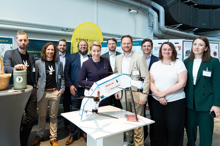 Gruppe von Personen in einem klinischen Umfeld steht um einen Tisch mit medizinischem Modell und verfolgt eine Demonstration.