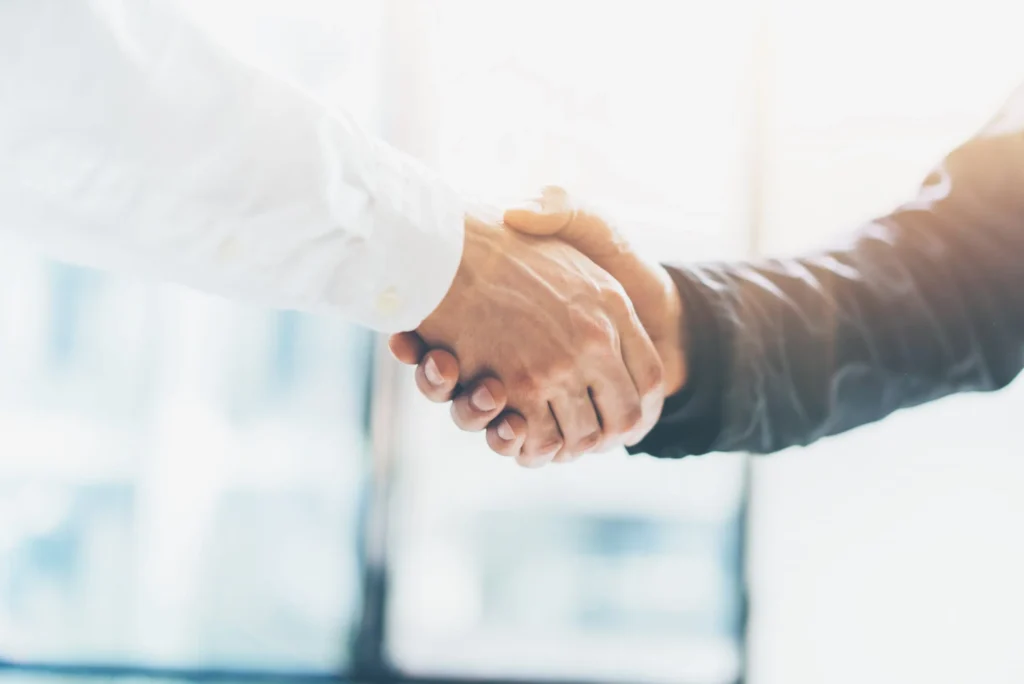 Zwei Personen geben sich die Hand als Zeichen von Zusammenarbeit und Vertrauen.