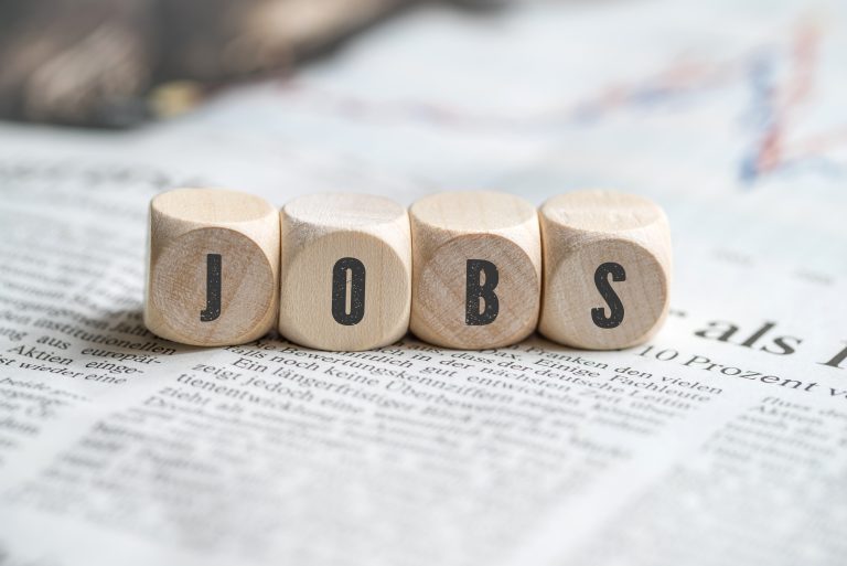 ier hölzerne Würfel auf einer Zeitung, die das Wort ‚JOBS‘ bilden, Symbol für Stellenangebote oder Karriereinformationen.