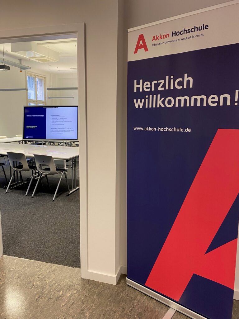 Aufsteller mit dem Schriftzug „Herzlich willkommen“ und Akkon-Logo im Eingangsbereich eines Seminarraums.