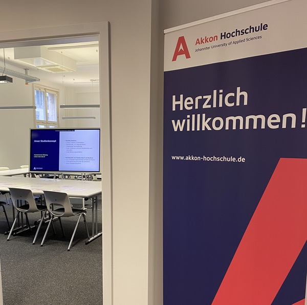Willkommensschild der Akkon Hochschule vor einem Seminarraum am Standort Berlin-Mitte.