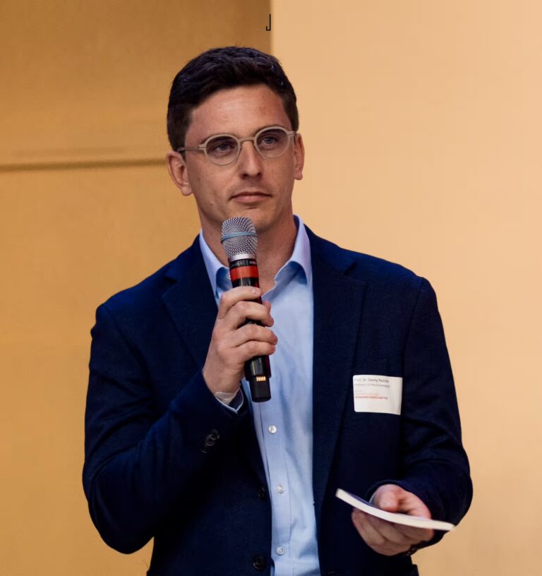 Mann im Anzug spricht mit Mikrofon bei einer Veranstaltung der Akkon Hochschule