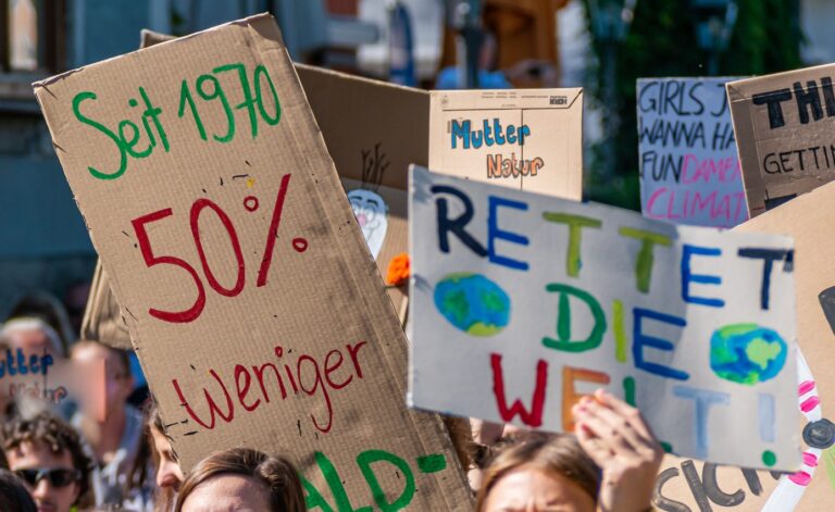 Handgehaltenes Plakat mit der Aufschrift „Stoppt Klimawandel“ und einer gezeichneten Erdkugel – Symbol für Klimaschutz und gesellschaftliches Engagement.