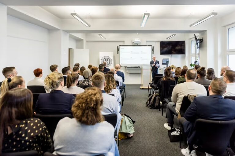 Studierende verfolgen eine Begrüßungsveranstaltung zum Studienstart in einem Seminarraum der Akkon Hochschule
