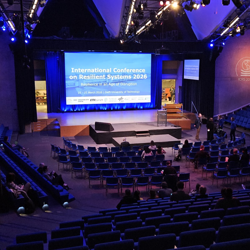 Konferenzsaal mit Bühne, Präsentationsleinwand und Publikum bei einer internationalen Fachkonferenz
