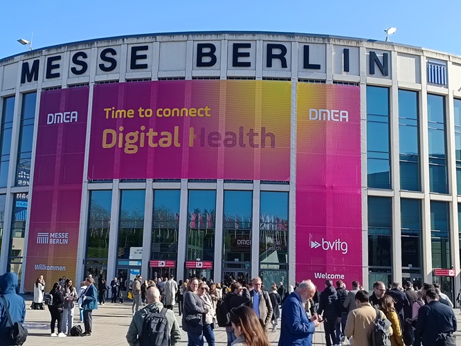 Eingang Messe Berlin mit großem Banner „DMEA – Connecting Digital Health“ und Besucherinnen und Besuchern.