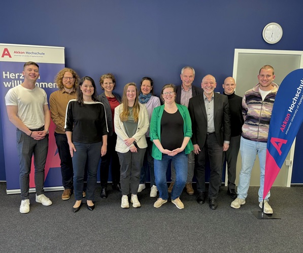 Gruppe von Teilnehmenden und Organisator*innen steht gemeinsam für ein Gruppenfoto in einem Innenraum