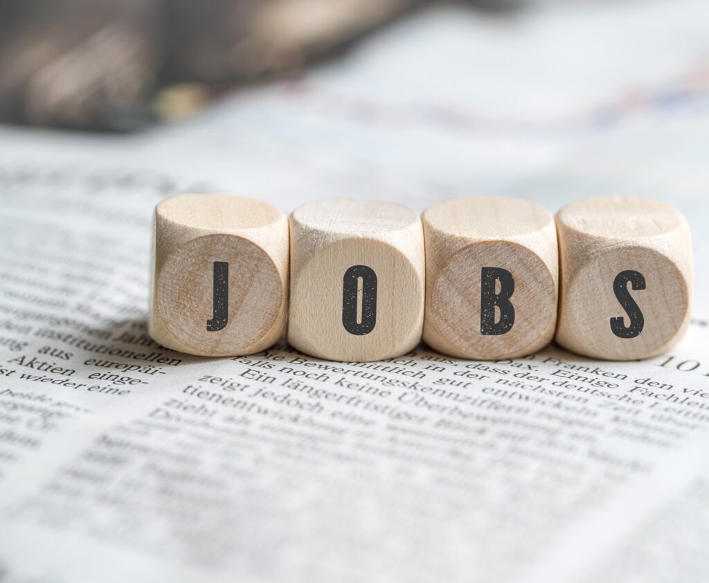 Holzwürfel mit den Buchstaben „JOBS“ auf einem Dokument als Symbolbild für Stellenangebote und Karriere an der Akkon Hochschule.