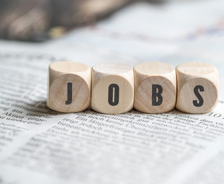 Holzwürfel mit den Buchstaben „JOBS“ auf einem Dokument als Symbolbild für Stellenangebote und Karriere an der Akkon Hochschule.