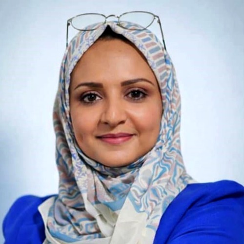 Porträt von Dr. Dalia Hyzam in einem blauen Oberteil und gemusterten Kopftuch vor hellem Hintergrund.