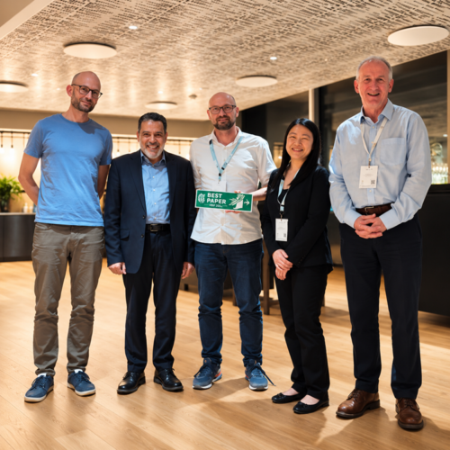 Fünf Teilnehmende des Human Behaviour in Fire Symposium 2026 stehen gemeinsam bei der Verleihung des Best Paper Awards. In der Mitte wird die Auszeichnung präsentiert.